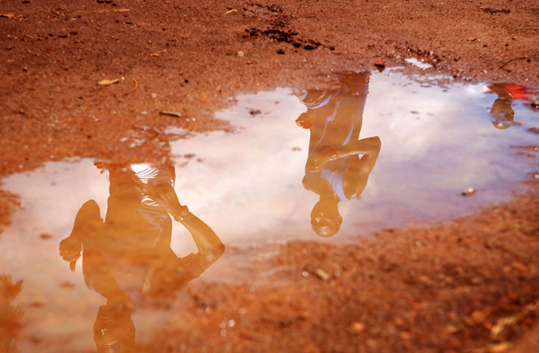 Members of Kenya's Men's National Cross Country team are reflected in a puddle while training around Moi Stadium's dirt track in Embu, Kenya on Tuesday, March 14, 2006. Thirty-eight of Kenya's best cross country runners attended the Embu camp to prepare for the upcoming World Championships in Japan on April 1st and 2nd.